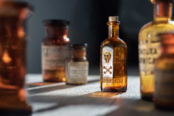 shutterstock_2338096013.jpg A collection of vintage glass bottles with labels on a wooden surface