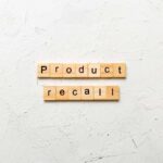 Wooden letter tiles spelling 'Product recall' on a textured surface