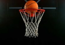 A basketball is about to enter a hoop against a dark background