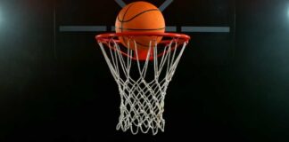 A basketball is about to enter a hoop against a dark background