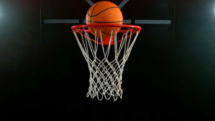 A basketball is about to enter a hoop against a dark background
