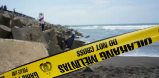 Yellow police tape by rocky ocean shore