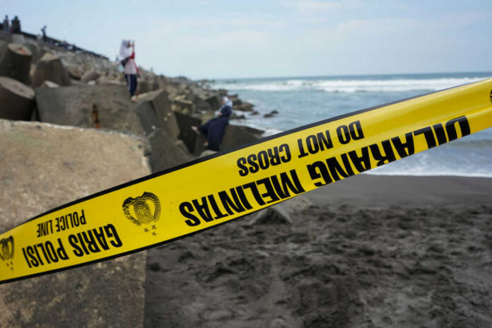 Yellow police tape by rocky ocean shore