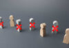 Wooden figures representing people with red crosses indicating exclusion