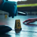 A detective examining evidence at a crime scene with markers on the floor