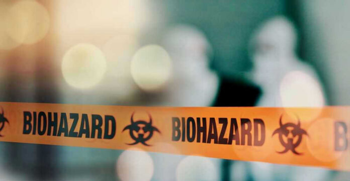 shutterstock_2357434791 Biohazard tape with blurred figures in background.