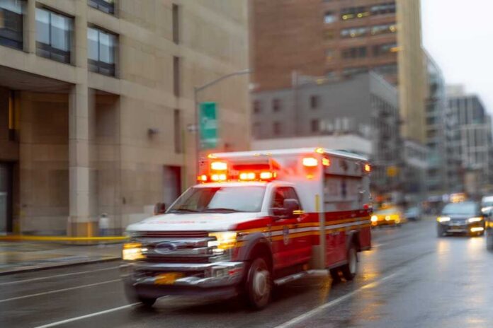 Ambulance with flashing lights driving on a wet city street