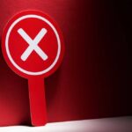 Red sign with a white 'X' symbol against a dark background